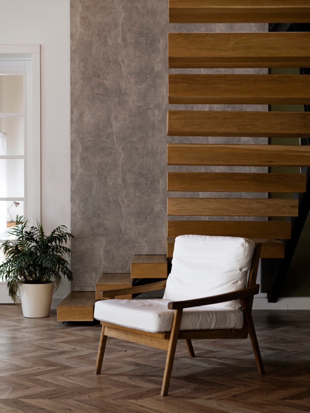 Salon en parquet point de Hongrie, fauteuil en bois et claustra d’escalier