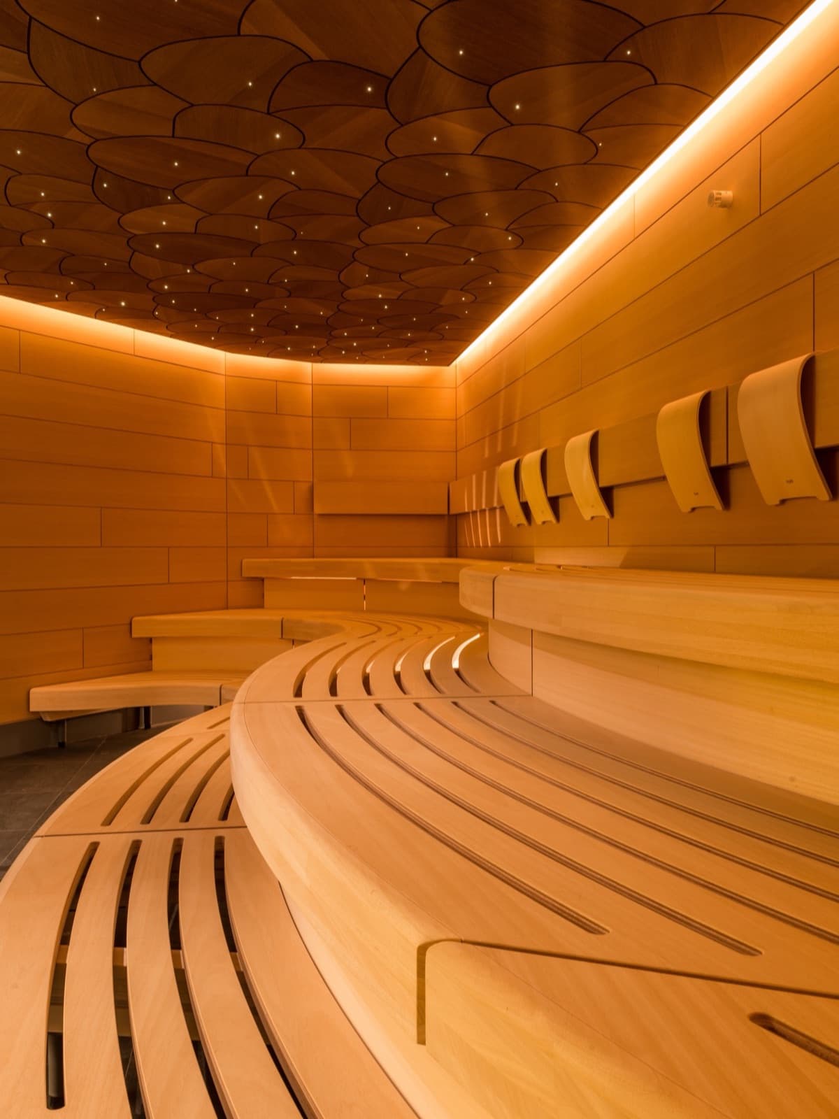 Espace spa entièrement en bois clair, banc courbe et plafond étoilé